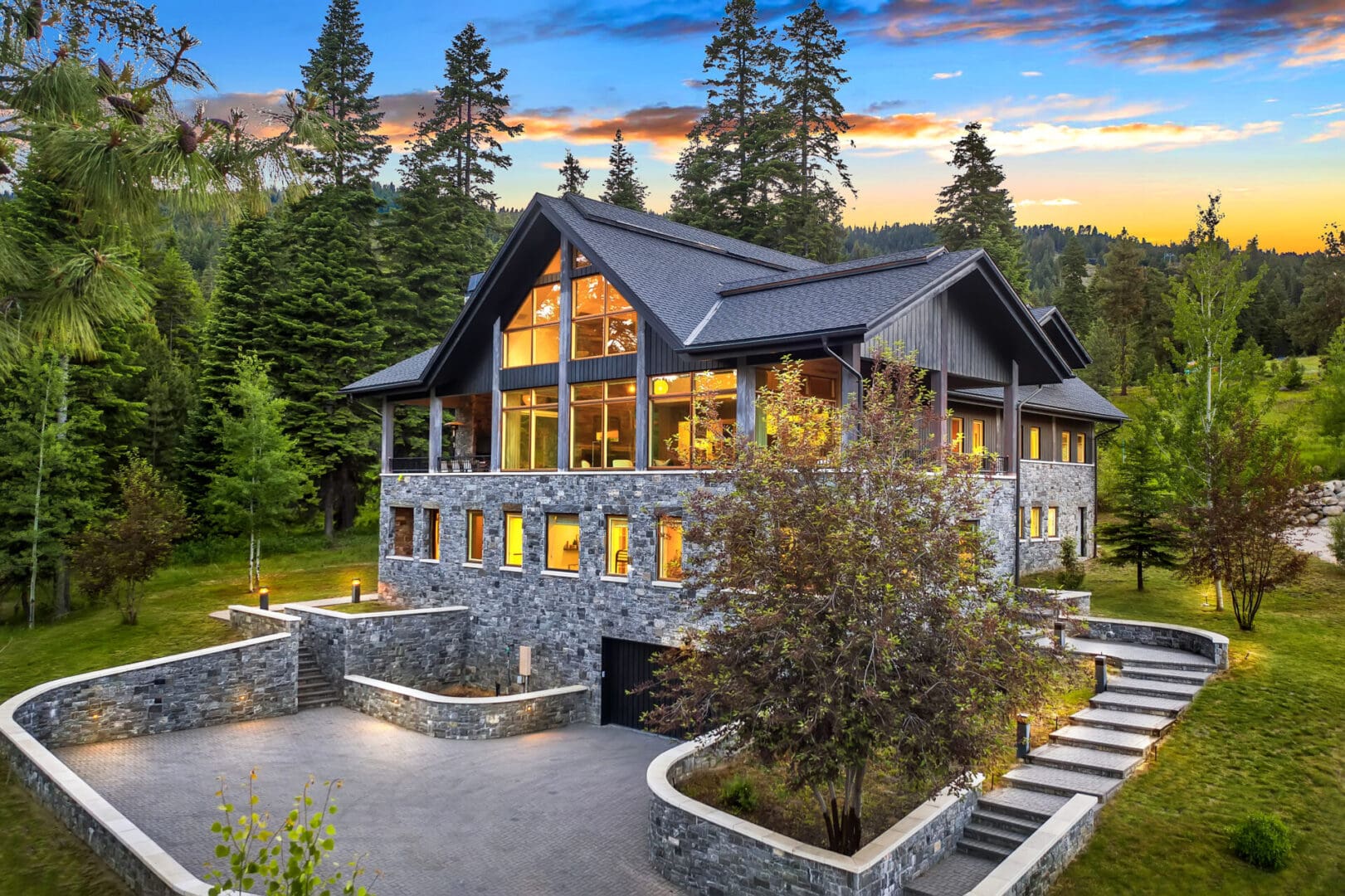 Modern mountain house with large windows, trees.